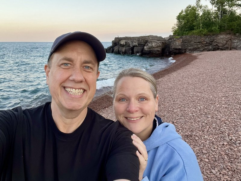 Justin and Jody taking a selfie above the pink cobbles of Iona's Beach at sunset