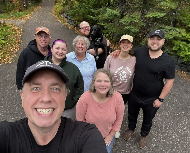 A selfie of Justin with the family on a wooded road in Duluth, fall colors all around